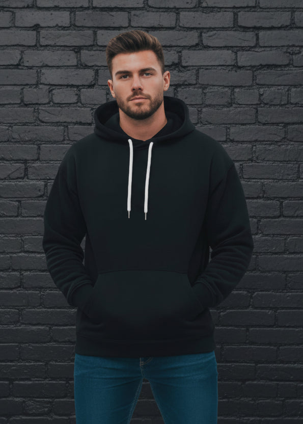 Man wearing a black hoodie and blue jeans against a gray background