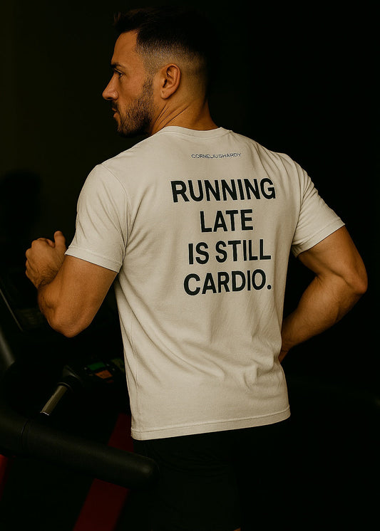 Person wearing a t-shirt with 'Running late is still cardio' text on the back, standing in a dark setting.