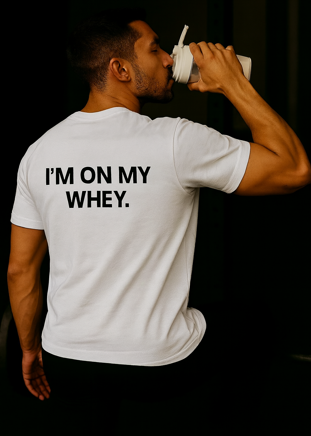 Man drinking from a container with 'I'm on my whey' text on a white t-shirt against a black background