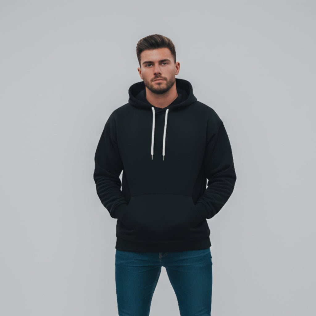 Man wearing a black hoodie and blue jeans against a gray background