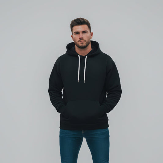 Man wearing a black hoodie and blue jeans against a gray background