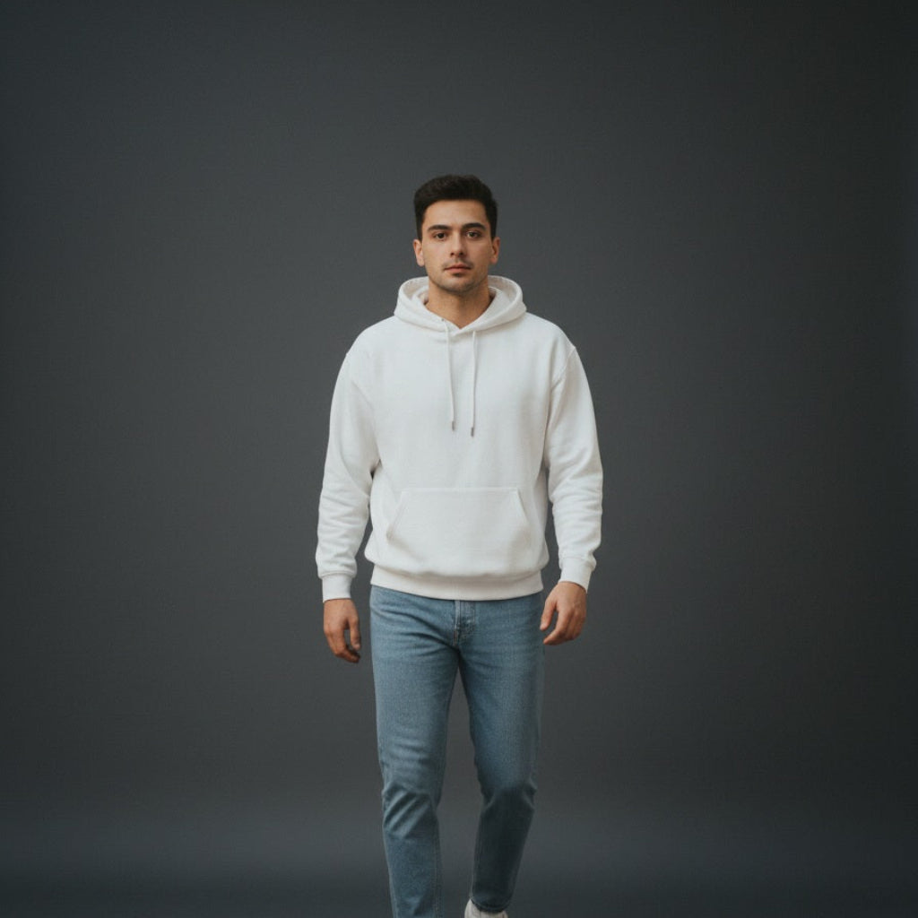 Man wearing a white hoodie and blue jeans standing against a dark gray background